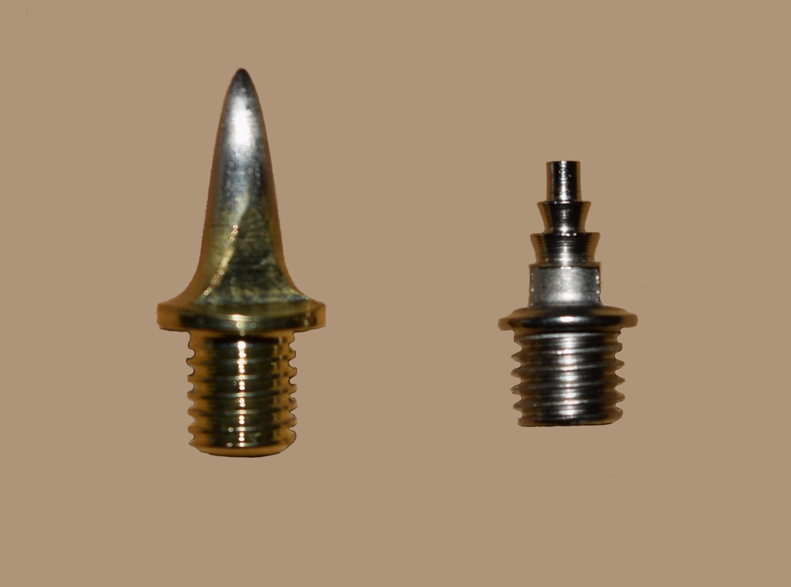 Different types of track spike pins laid out side by side, showing pyramid and tiered compression geometries
