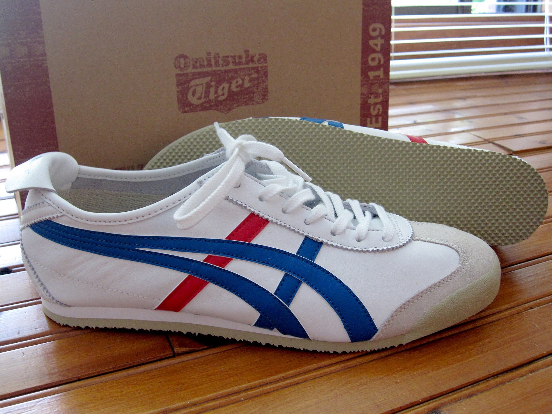 A pair of Onitsuka Tiger Mexico 66 shoes in white, blue and red showing the Mexico line stripes