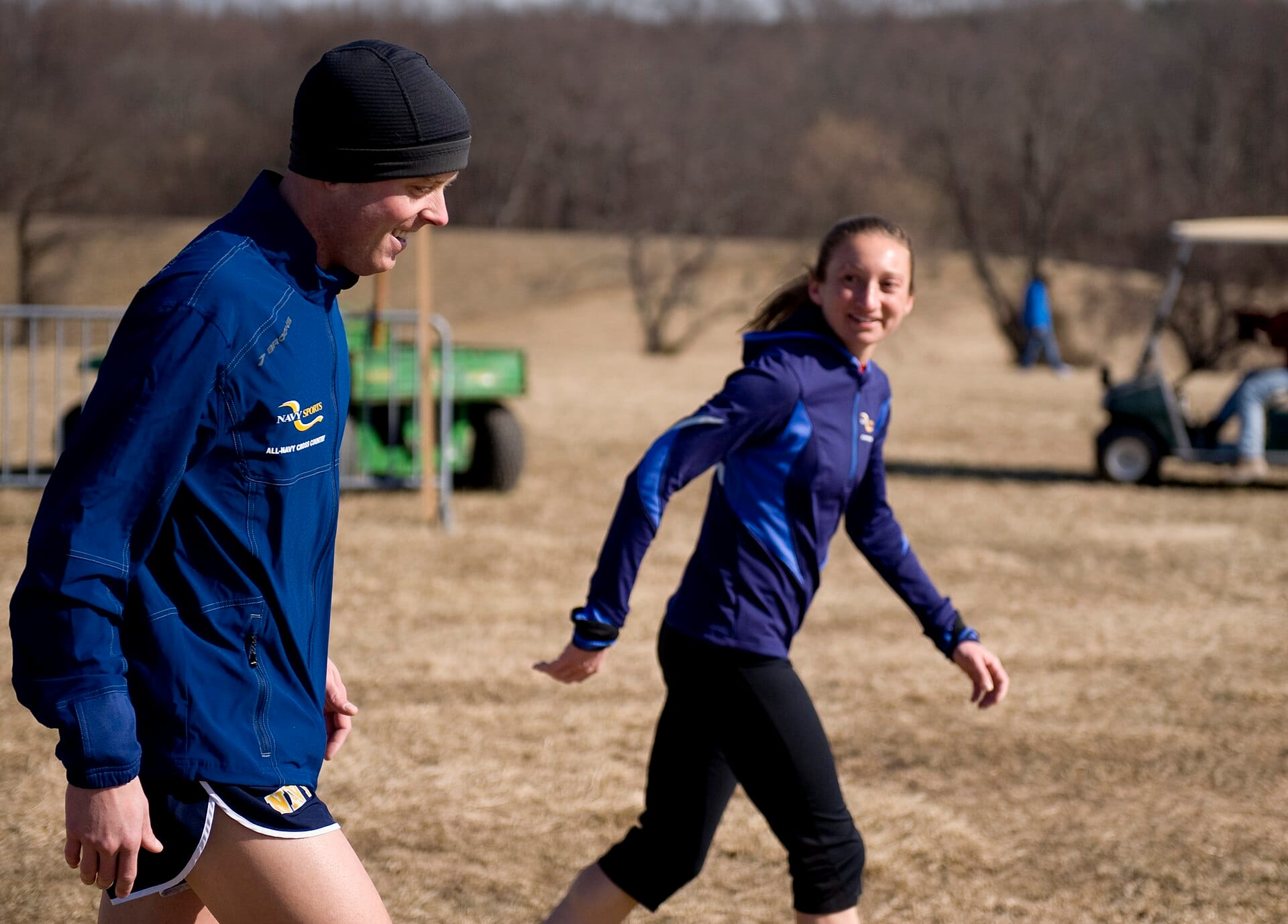 Two all-Navy cross country athletes walking a race course in team half-zip mid layers