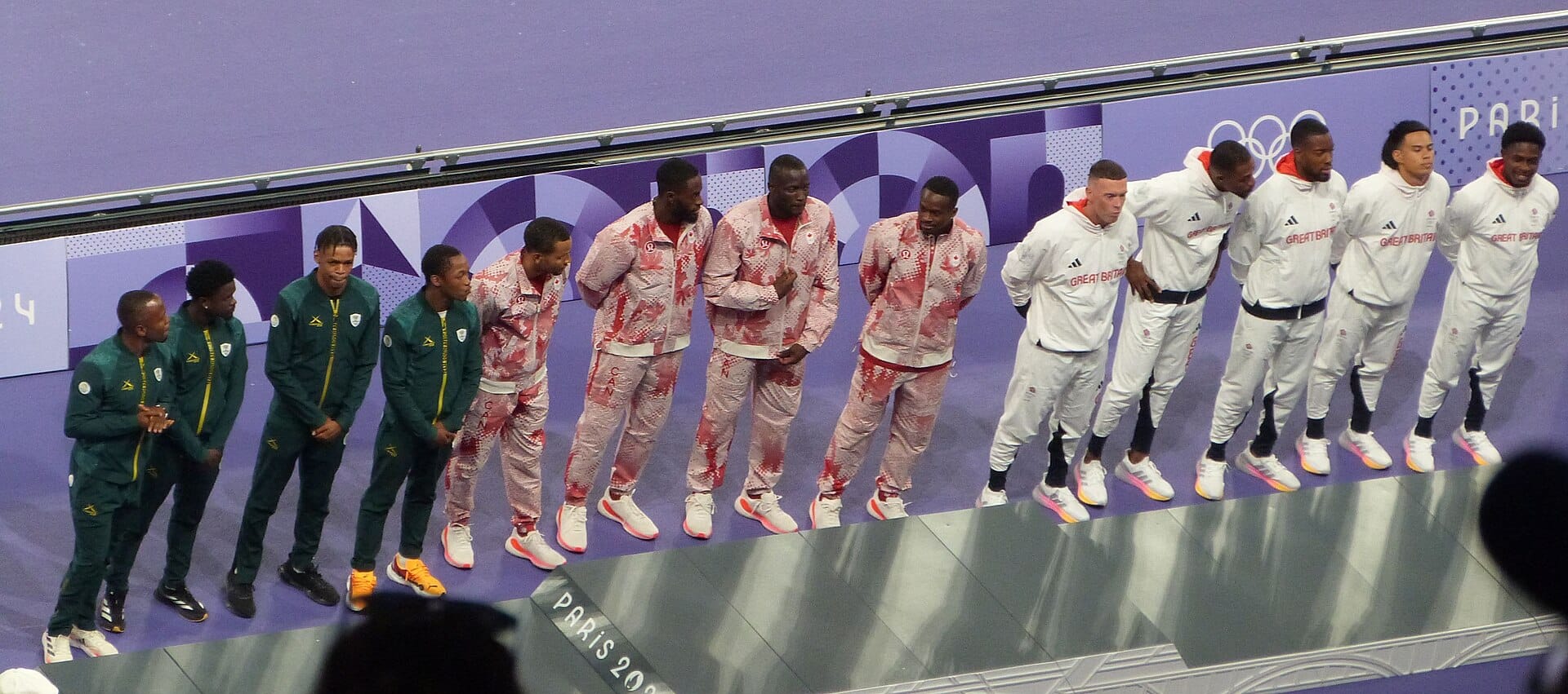 Three national teams in matching tracksuits on the Paris 2024 podium for the men's 4x100 relay