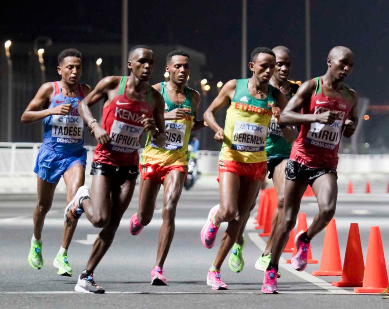 The lead pack of the men marathon at the 2019 World Championships in Doha at night, with Lelisa Desisa and Mosinet Geremew of Ethiopia